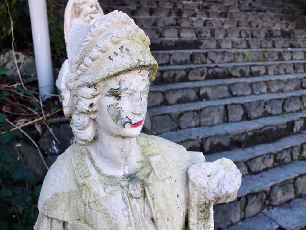 A statue of a woman. She is mostly white but her lips have been painted red.