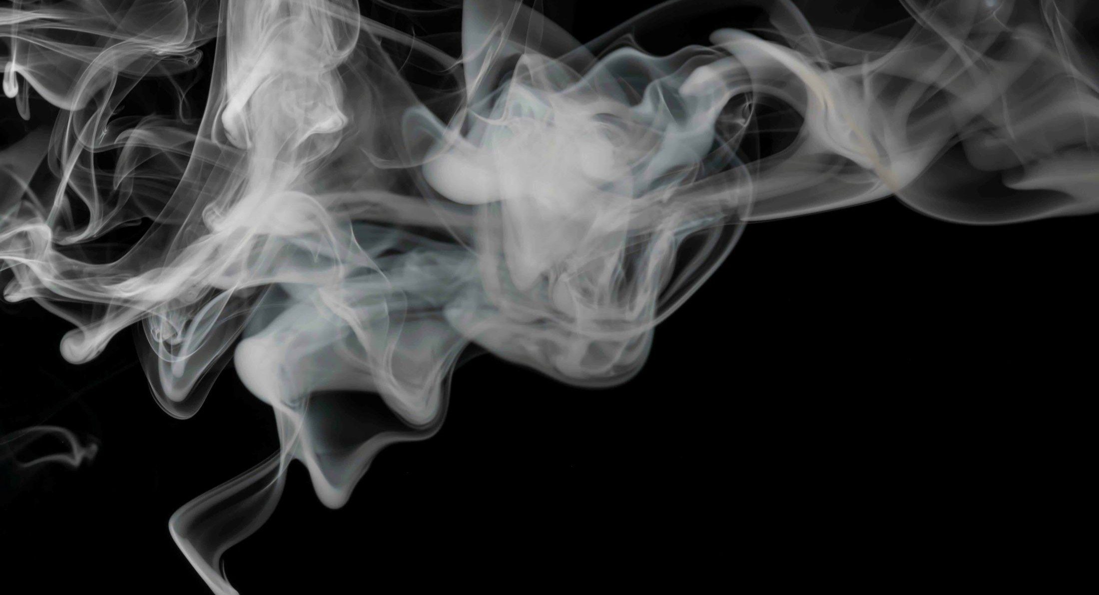 Grey tendrils of smoke occupy the top quadrant of the frame against a black background.