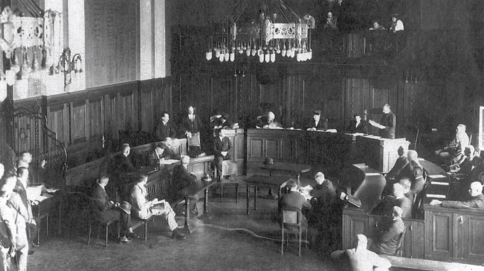 An old black and white photo of a wood-panelled courtroom during a trial.