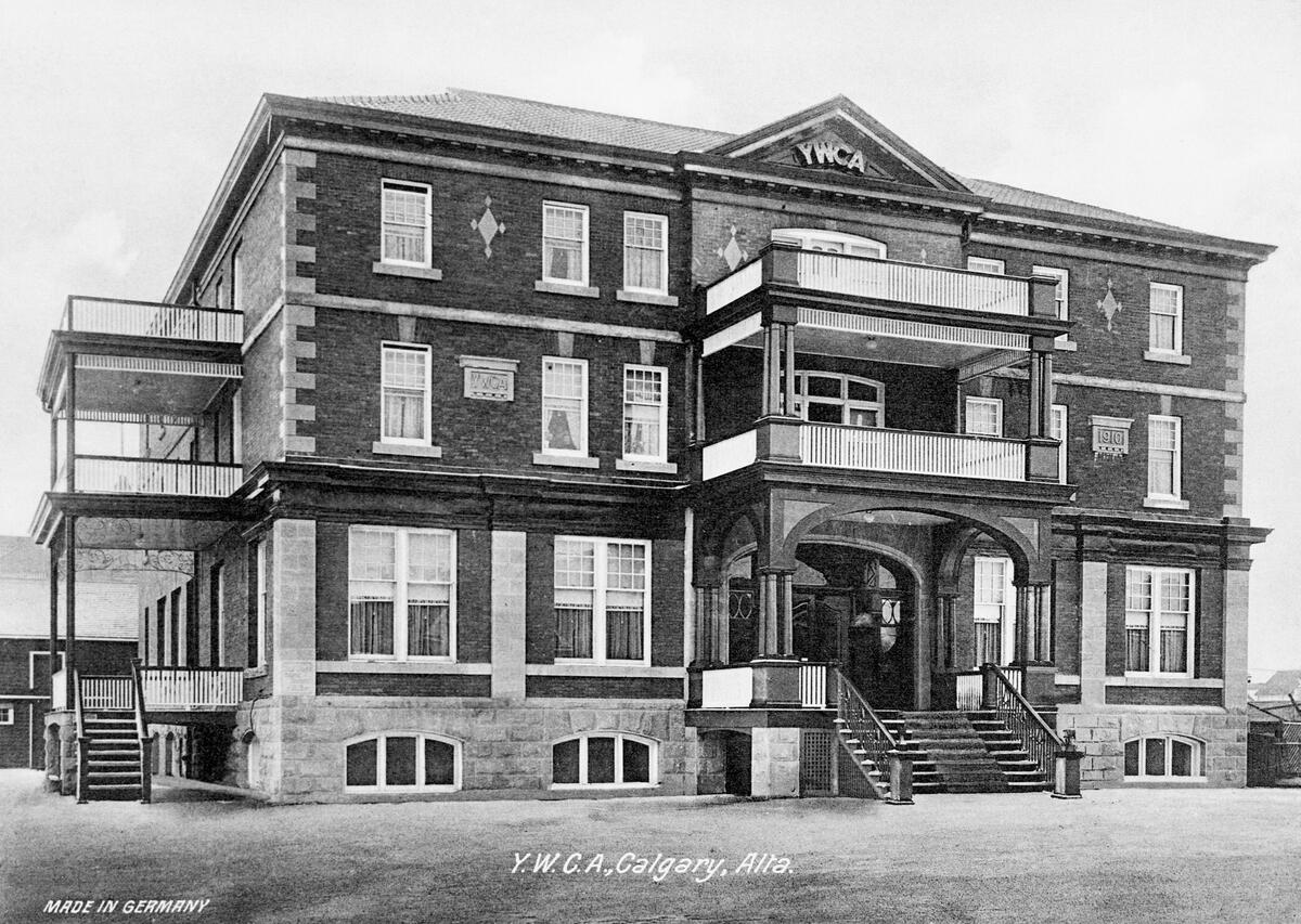A black-and-white photograph of a large brick building features “YMCA” at its peak.