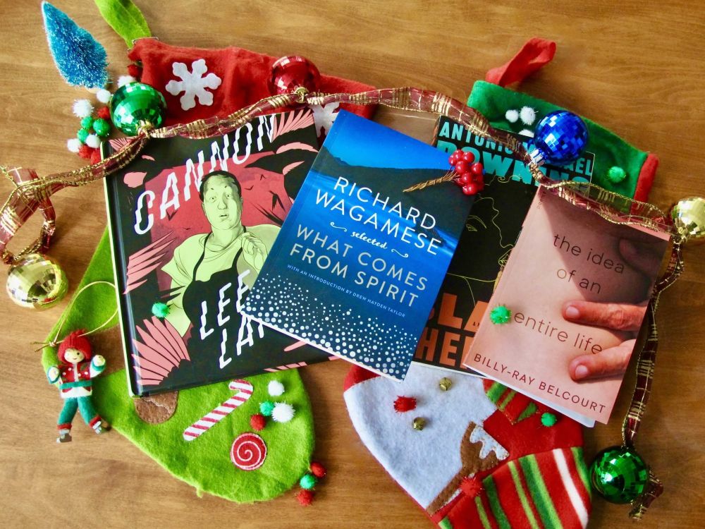 From left to right: &ldquo;Cannon&rdquo; by Lee Lai, &ldquo;What Comes from Spirit&rdquo; by Richard Wagamese, &ldquo;Black Cherokee&rdquo; by Antonio Michael Downing and &ldquo;The Idea of an Entire Life&rdquo; by Billy-Ray Belcourt. The books are on top of stockings, decorated with a garland with Christmas ornaments.