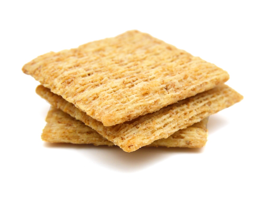 A stack of three woven wheat crackers are stacked against a white background.