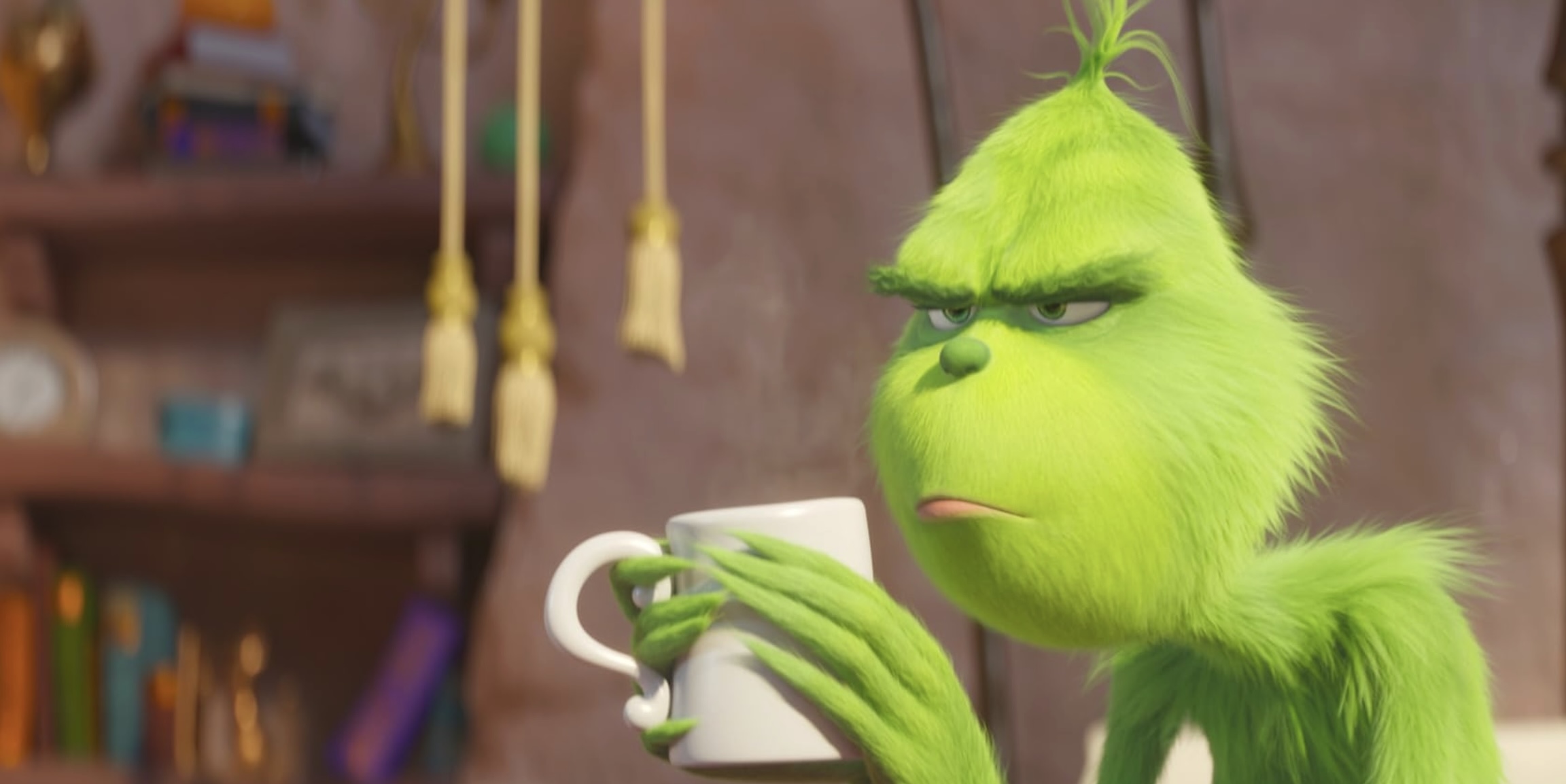 A digital still of a furry green creature with a furrowed brow sitting hunched. He is frowning and holding a white coffee mug.