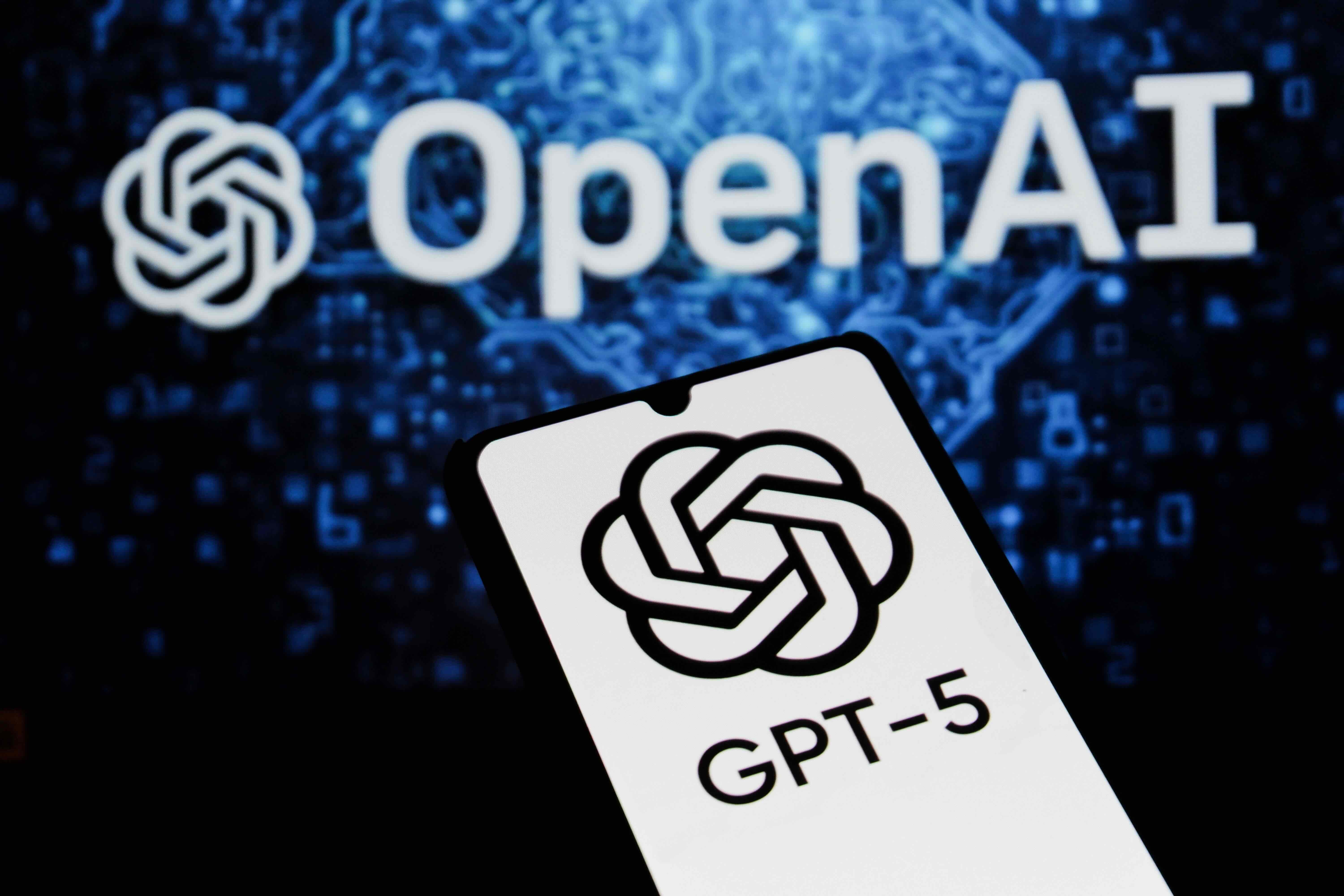 A smartphone with a white screen holds an interface that reads &ldquo;ChatGPT-5&rdquo; against a dark blue and black background with the word &ldquo;OpenAI&rdquo; in white.