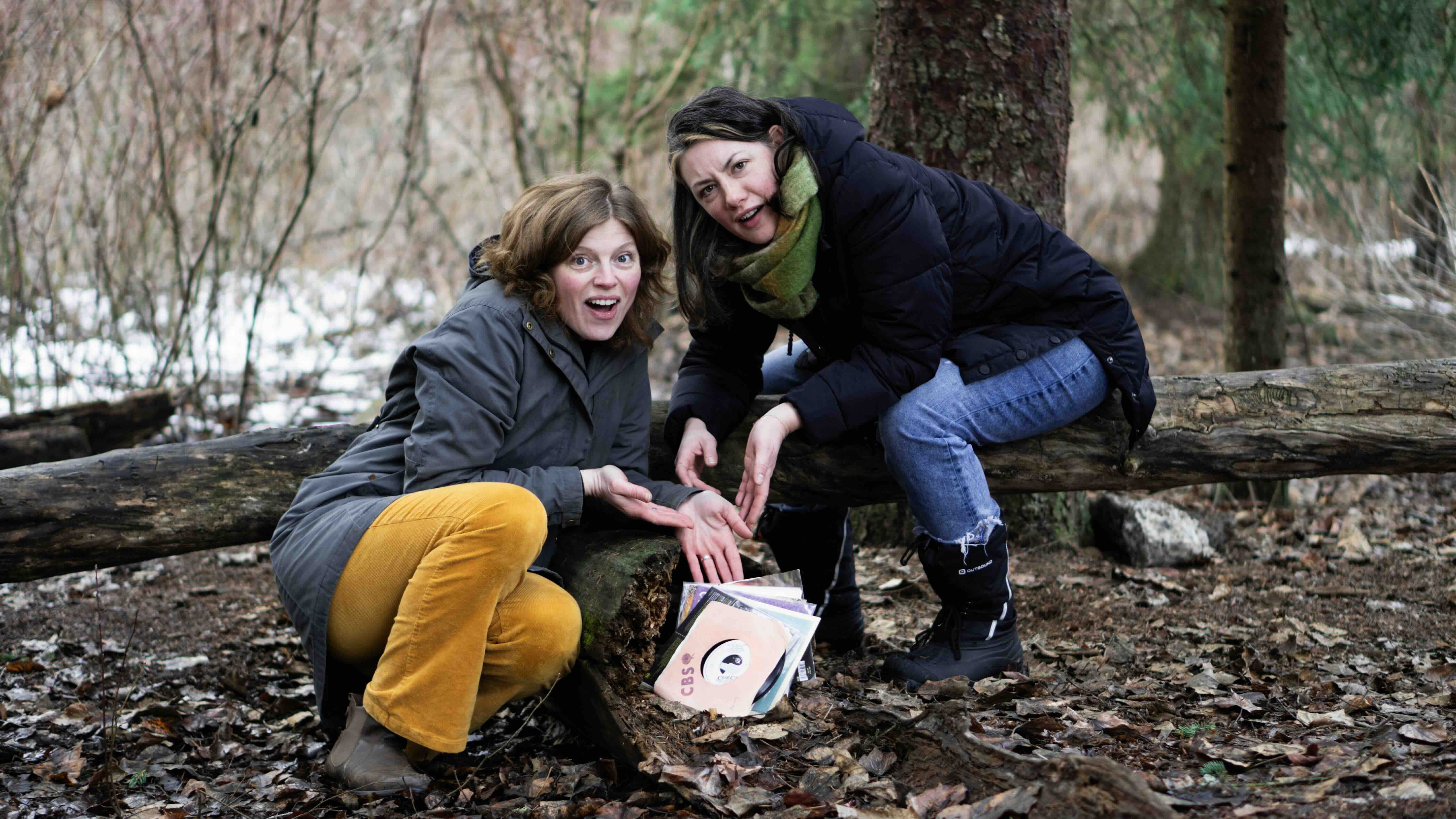 Naomi Kavka, at left, and Pam Haasen, at right, pose near a small pile of vinyl music in the woods.