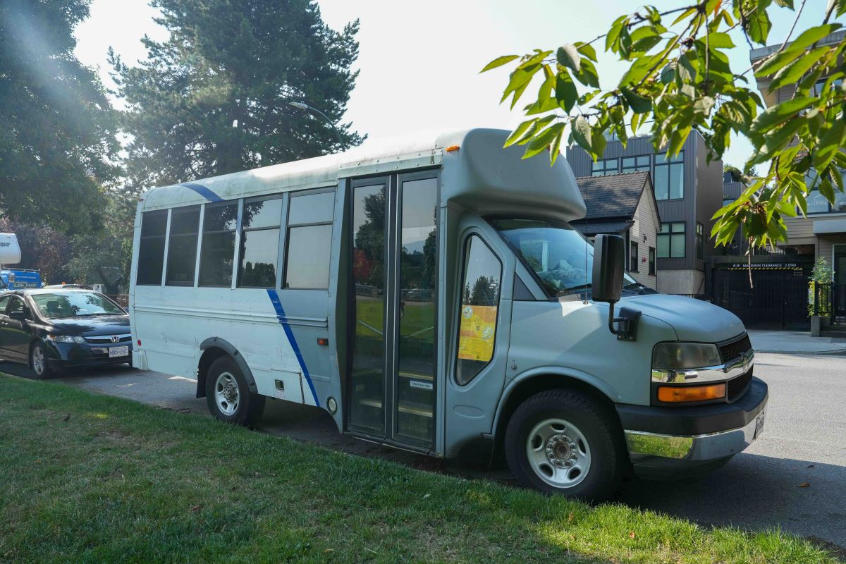 Top: Zoe Diomis stands in front of the open doors of a small blue repurposed bus. She has long dark hair and is wearing a cream coloured ribbed T-shirt. Bottom: a repurposed grey and blue small bus is parked on the side of a leafy residential street.