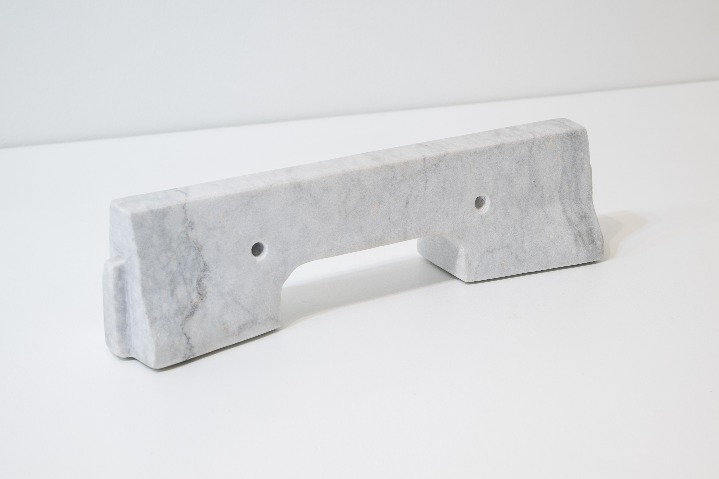 A white marble sculpture resembles a concrete barrier one might find in a city street or construction site.