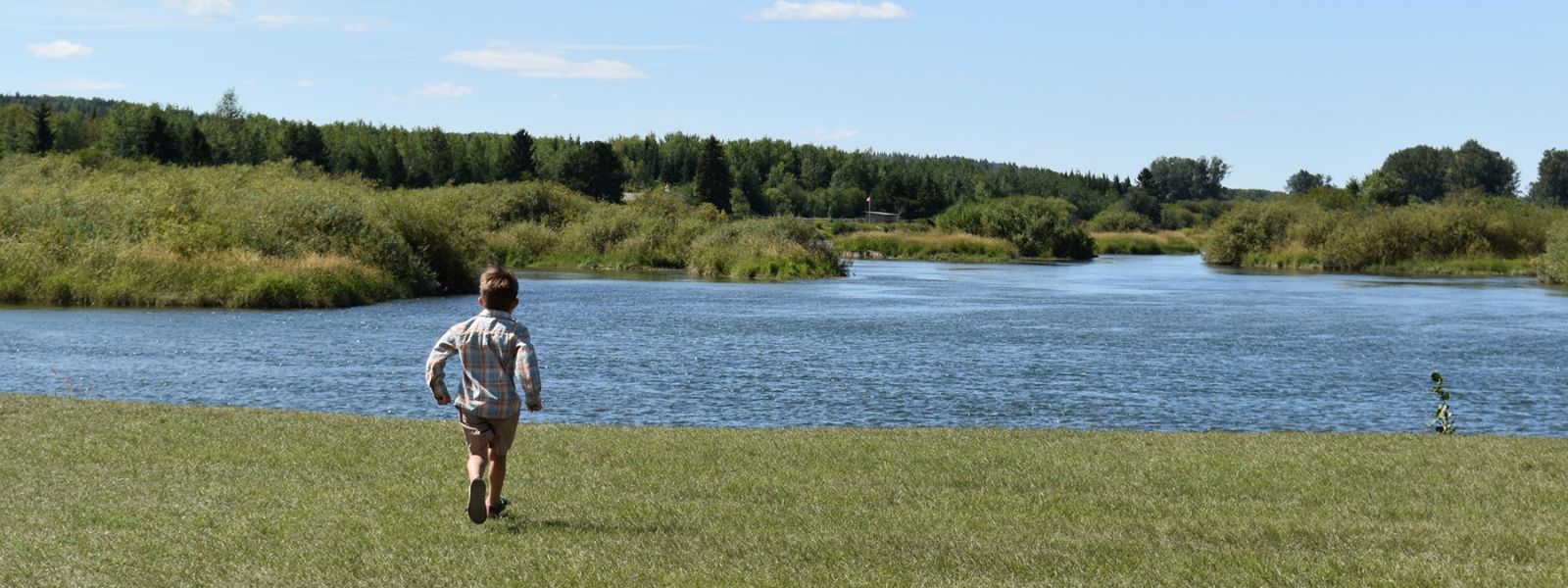 A small child runs toward the Nechako River. 