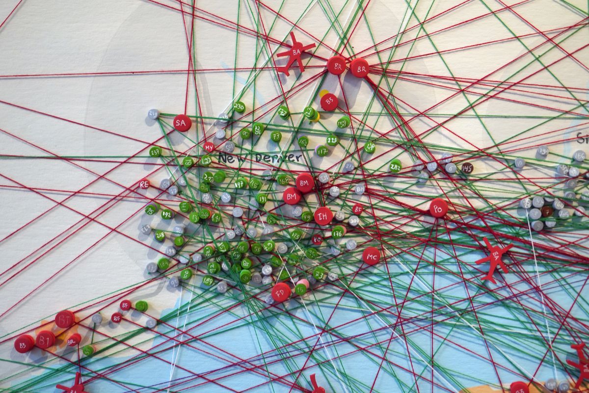 Red and green pins and string overlay a map showing a lake and its shore. The words New Denver can be seen beneath some of the string.