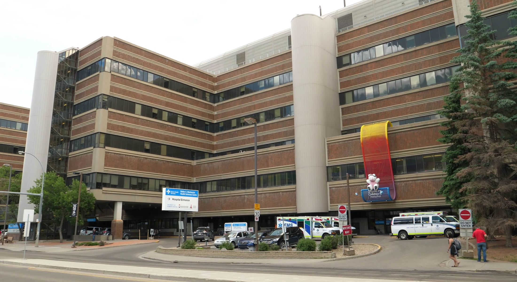 The exterior of Stollery Children&rsquo;s Hospital on a cloudy day. The multi-storey building has a dark and light brown exterior with blue and white hospital signage outside.