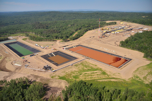 An overhead shot of a fracking site near Fort St. John, featuring three pools of water; two are clay-coloured, one is green.