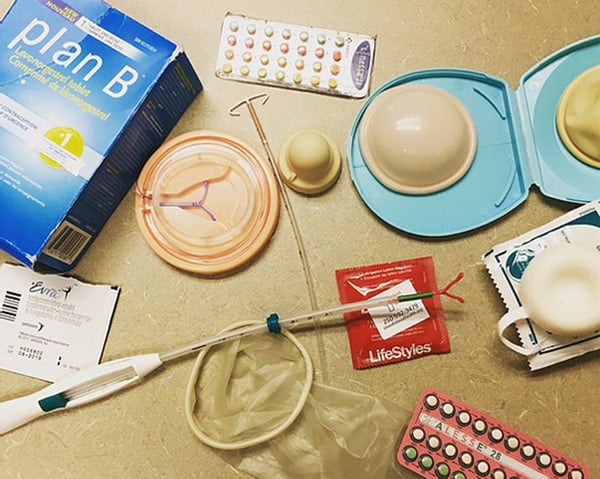 A variety of contraceptive products are arrayed on a table