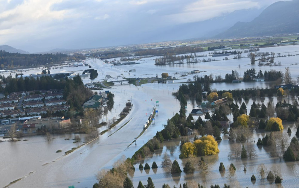 An aerial view shows a flooded highway, houses and farms.