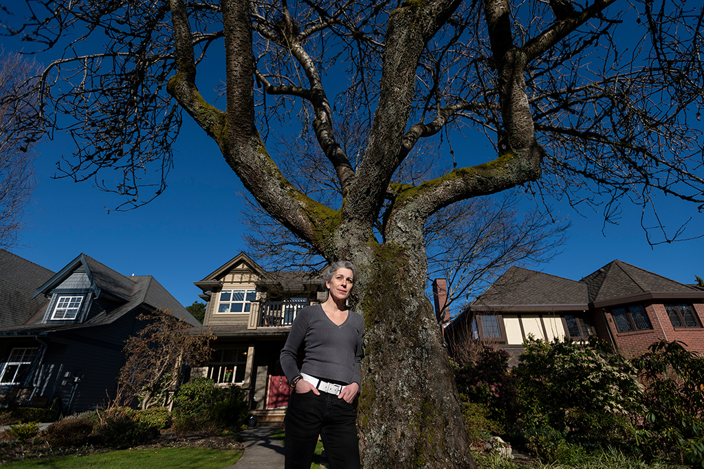 Jennifer Thompson stands against a tree before a house on a residential street.