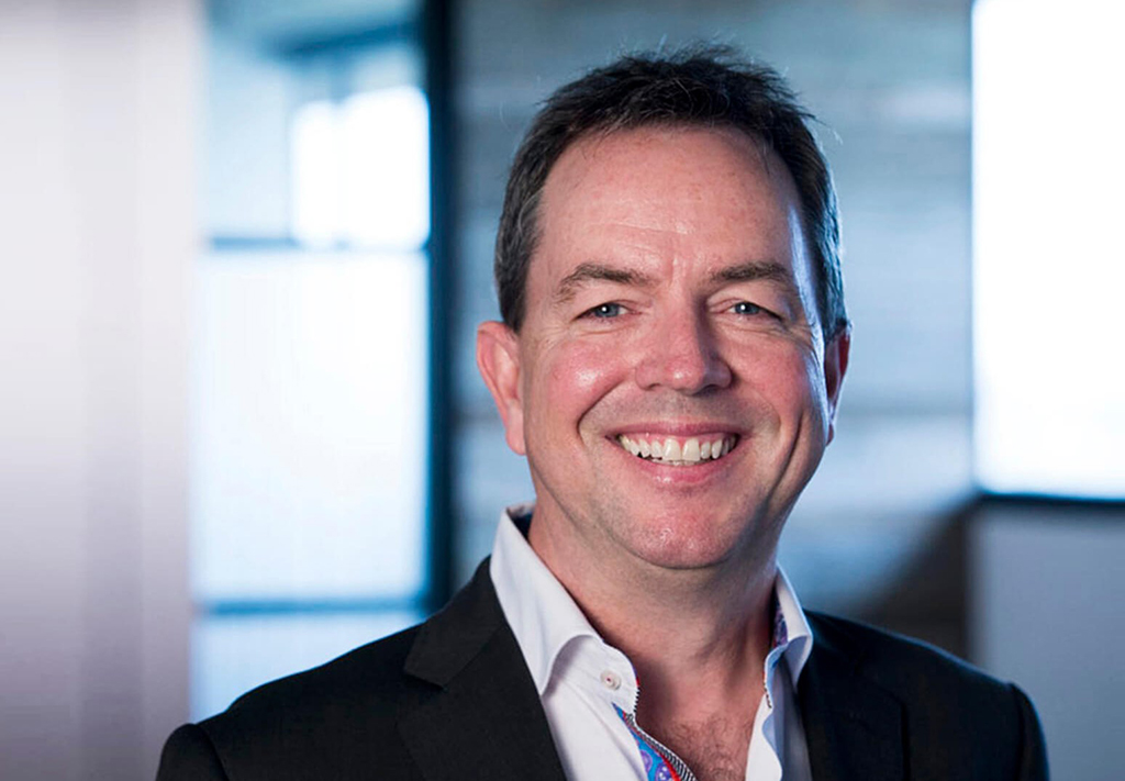 Athabasca president Peter Scott smiles in a dark suit and white shirt, headshot in focus.