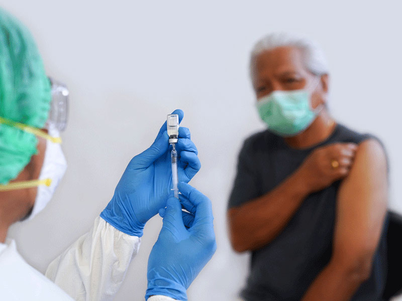 A nurse preparing a vaccination as a patient waits.