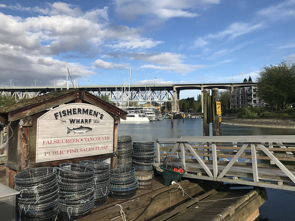 A sign reads “Fisherman’s Wharf, False Creek, Vancouver.” In the background is Granville Bridge and False Creek. In the foreground, crab pots.
