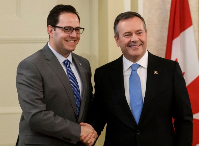 Alberta’s Advanced Education Minister Demetrios Nicolaides stands with Premier Jason Kenney, as they shake hands and smile. 