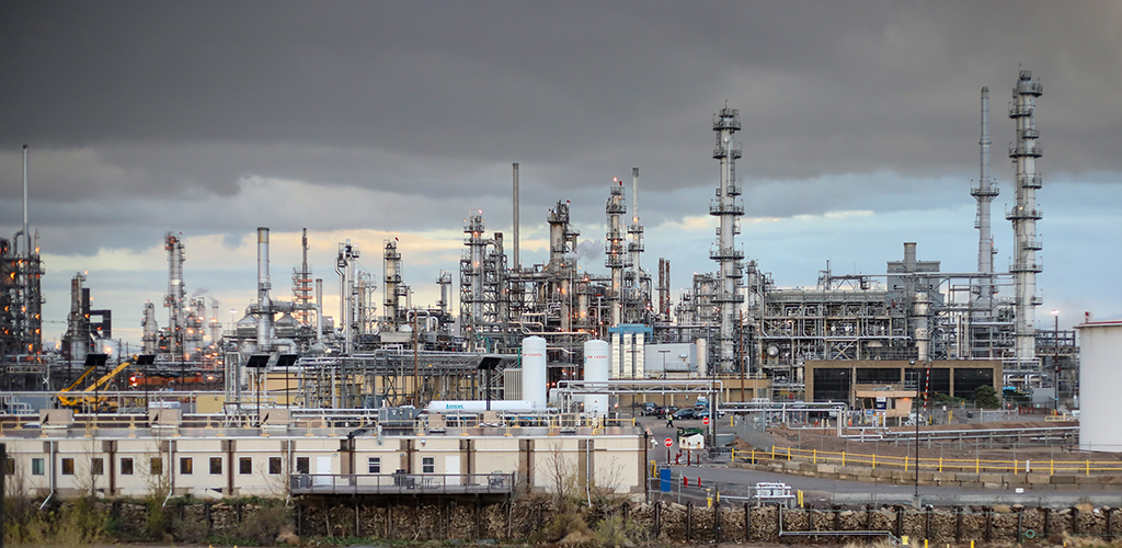 Against grey skies, the dense collection of pipes and smokestacks that make up the Suncor oil refinery in Commerce City, Colorado.