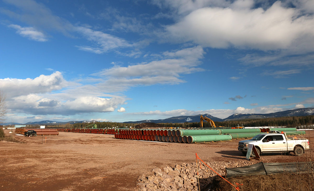 A cleared dusty area with stacks of pipes.