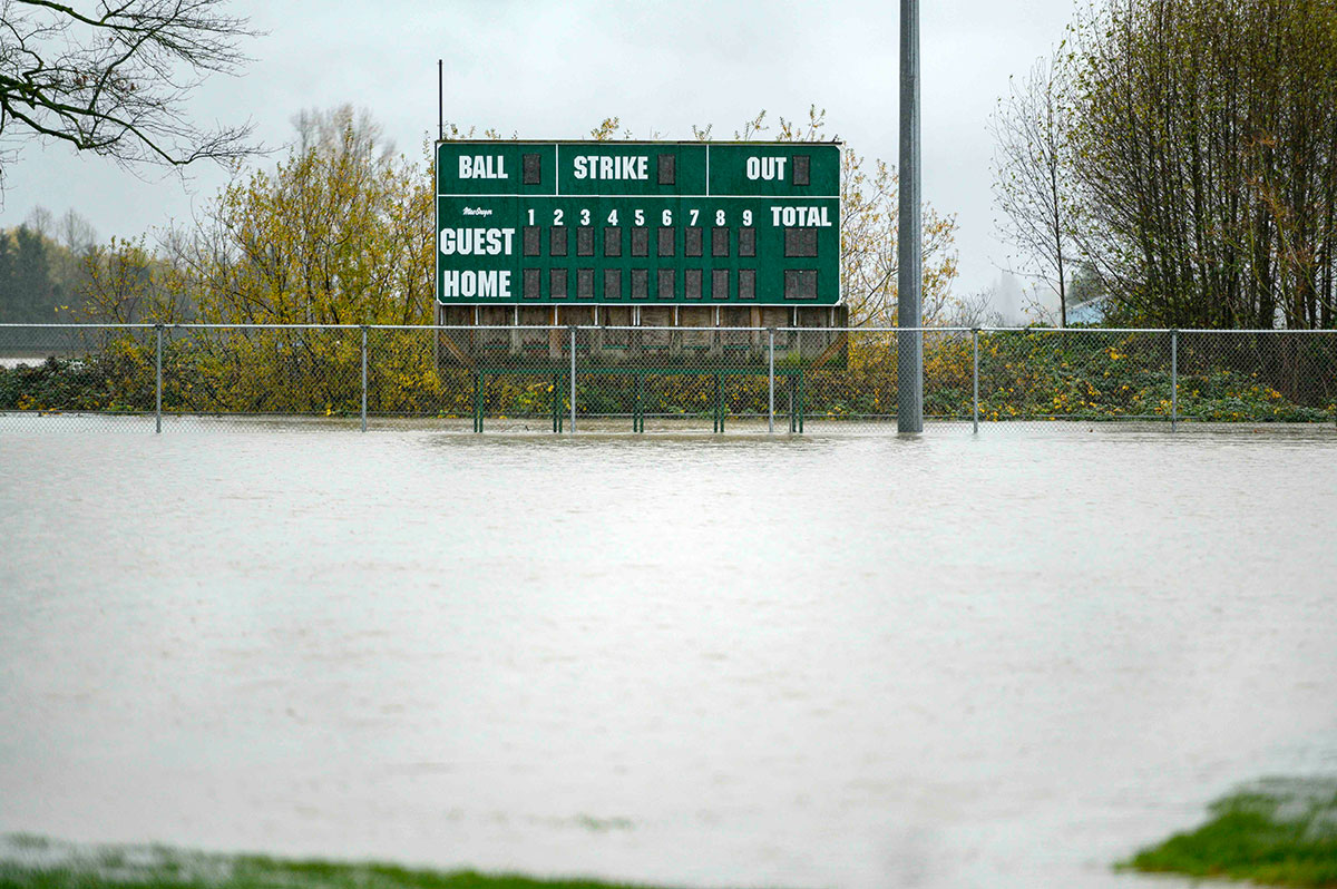 A baseball scorecard is visible above a flooded baseball diamond. The scorecard is green with white letters and numbers.  
