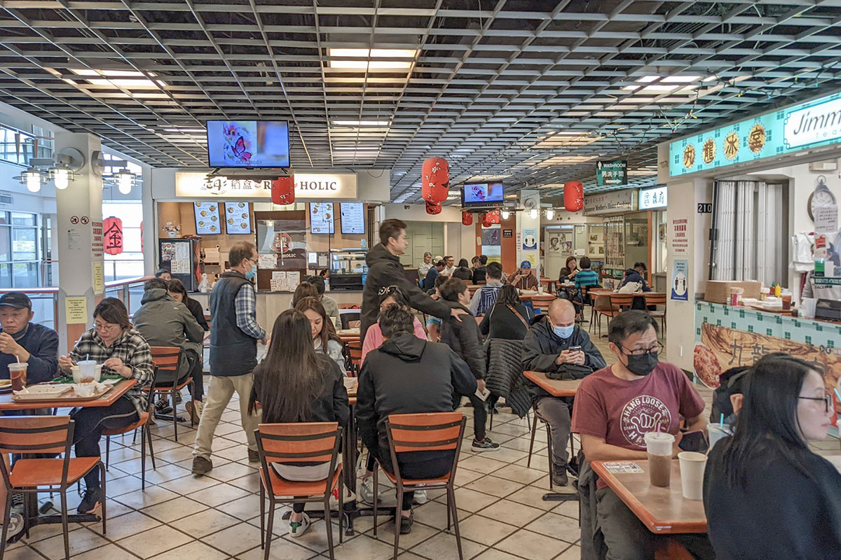A cozy food court on the upper floor of a non-descript office building. The tables are packed with hungry Hongkongers sipping milk teas and lemon teas as they wait for their meals from mom-and-pop stalls.