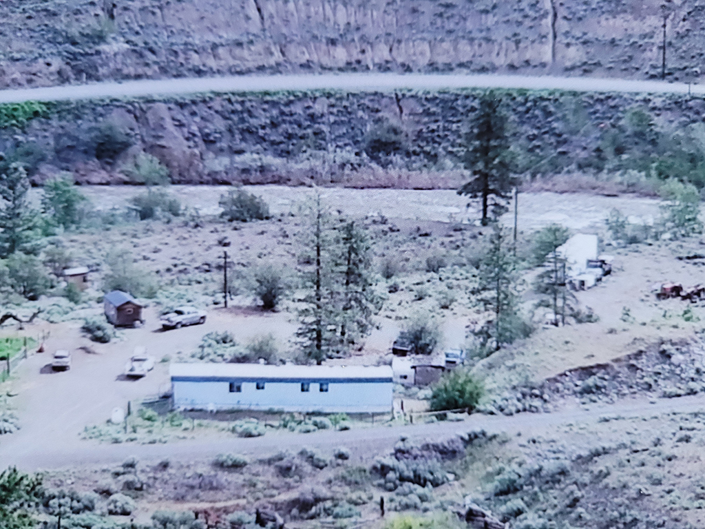 A low-quality older aerial photo shows the home with the river much farther away in the background.