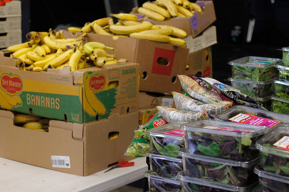 A table with boxes of bananas on top in the background; in the foreground, a bit blurry, salad mix boxes.