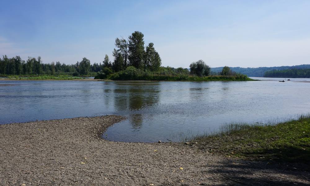 The Nechako river sits beside a sand embankment. 