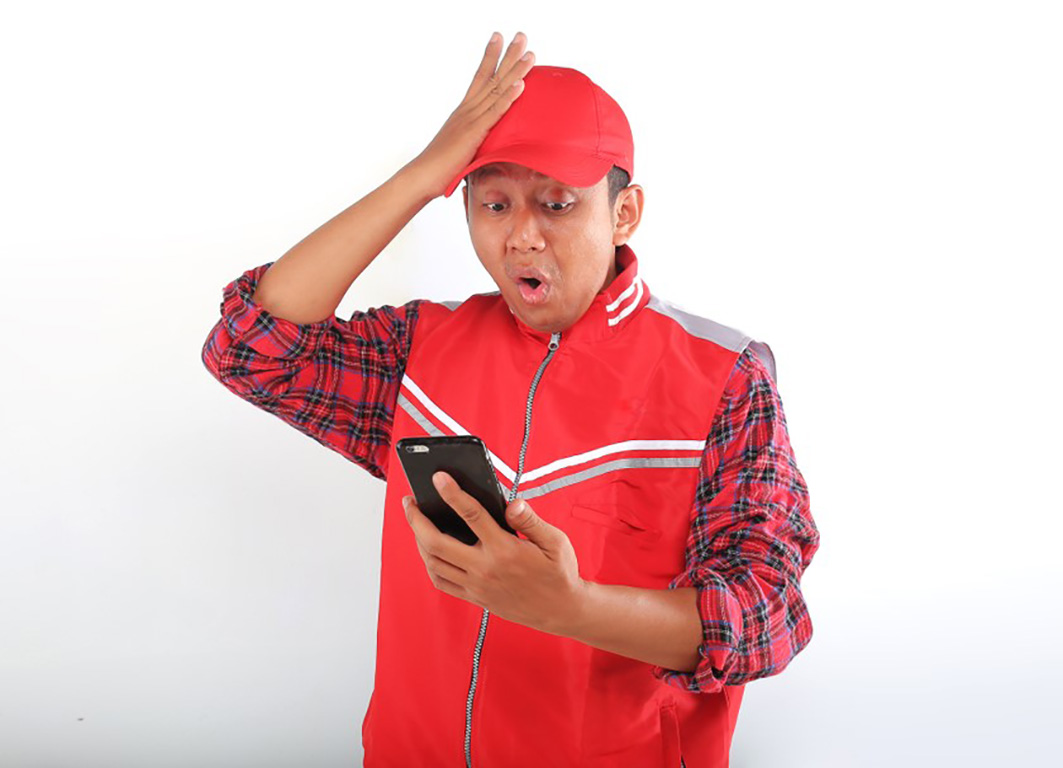A man dressed in red wears a shocked expression while looking at his phone.