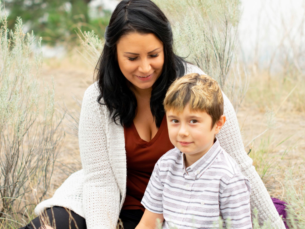 A mother and son sit outside for a family photo outdoors.    