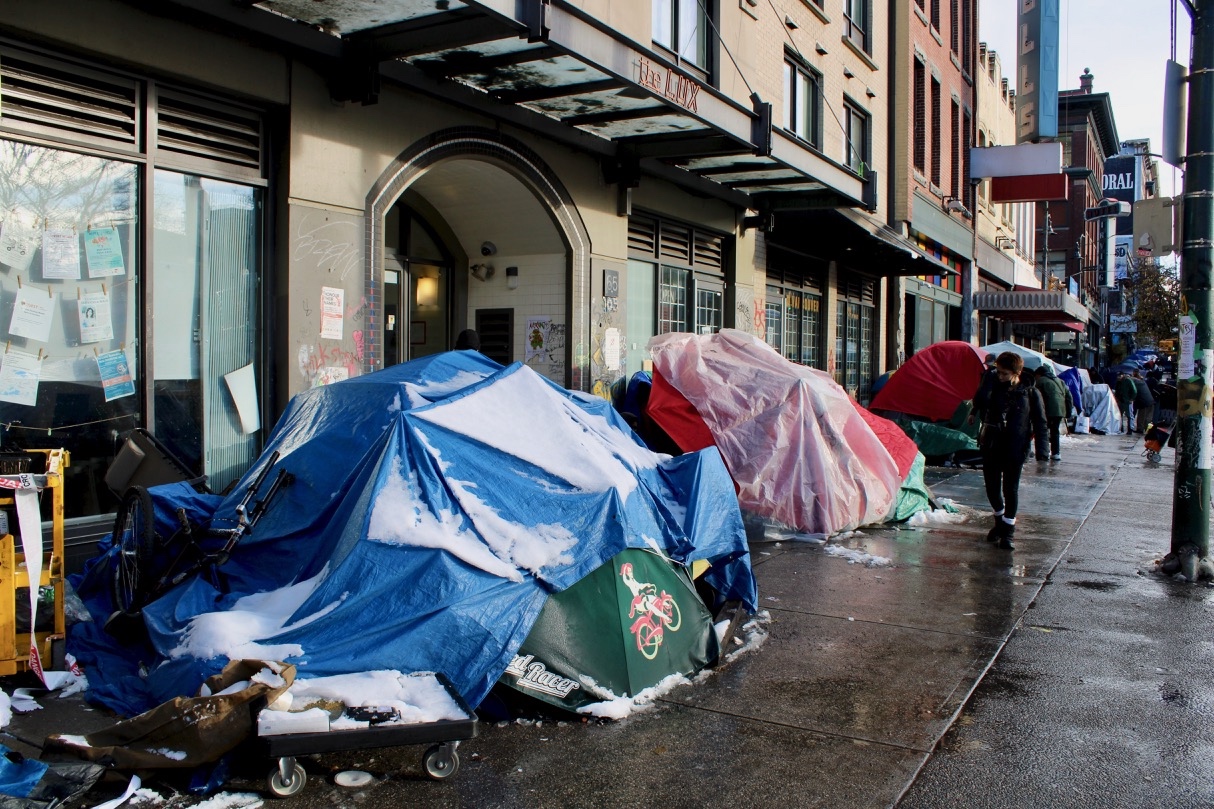 Tents and makeshift shelters stretch along a wet sidewalk in Vancouver’s Downtown Eastside.
