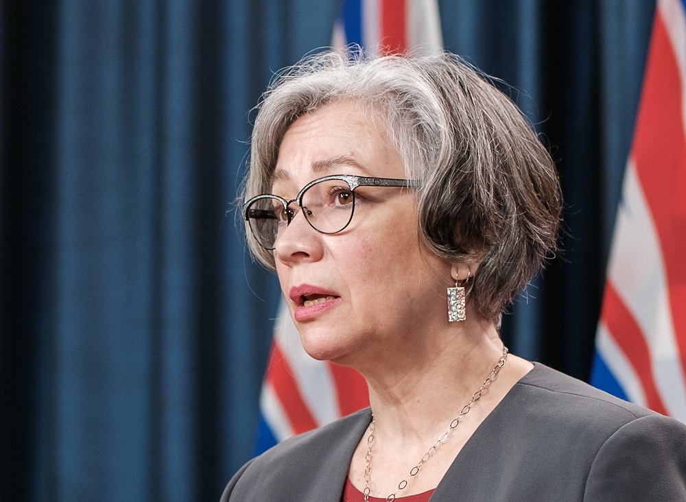 Close-up of a woman who looks like a politician with the B.C. and Canada flags behind her.