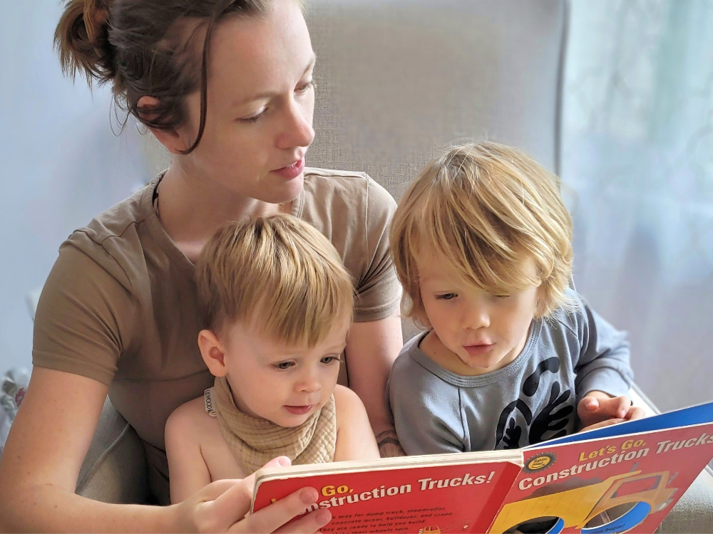 A mother reads a book called, ‘Let’s Go! Construction Trucks!’ 