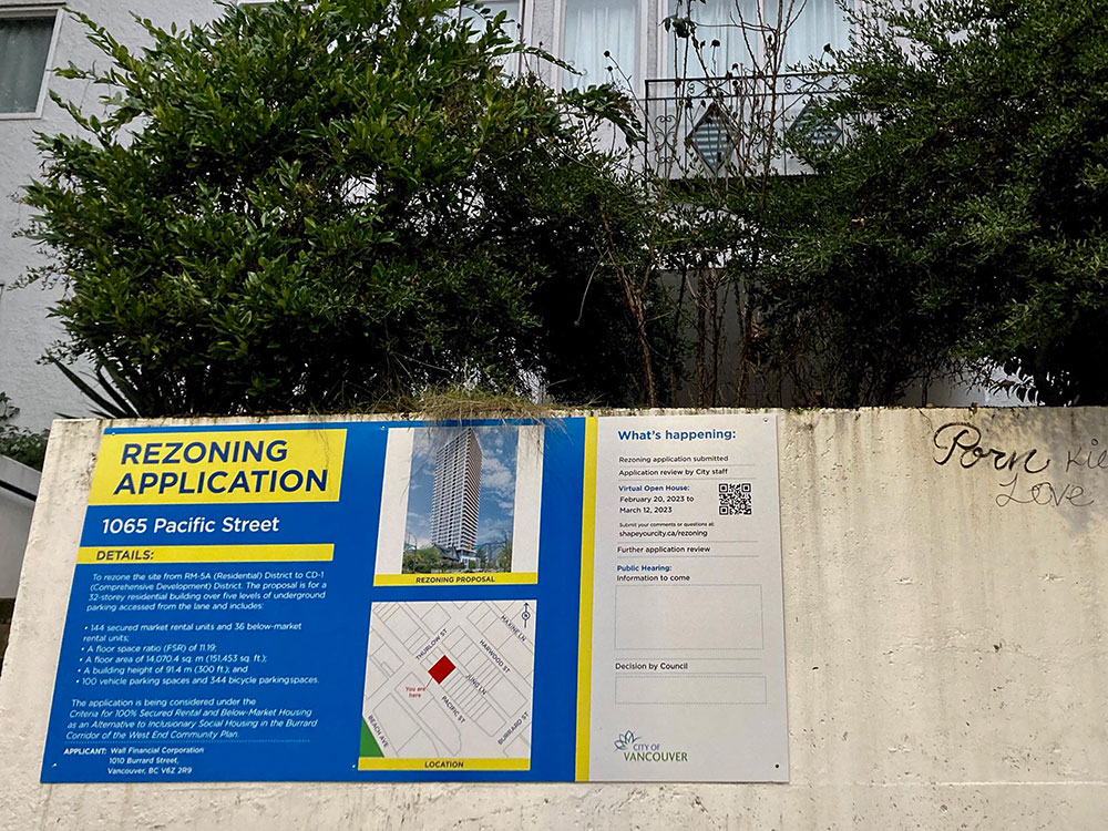 A redevelopment sign is fixed to a retaining wall in front of an older apartment building on Pacific Street in Vancouver’s West End.