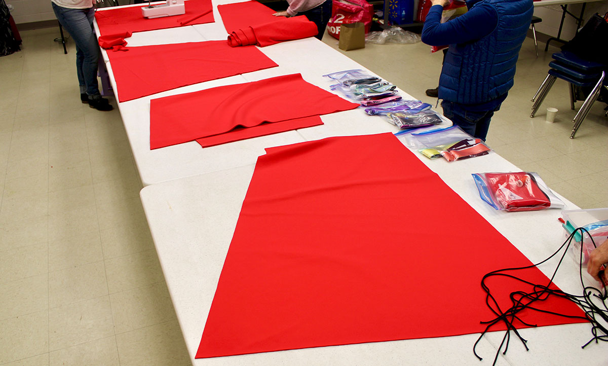 Bolts of red fabric lay across a plastic folding table.