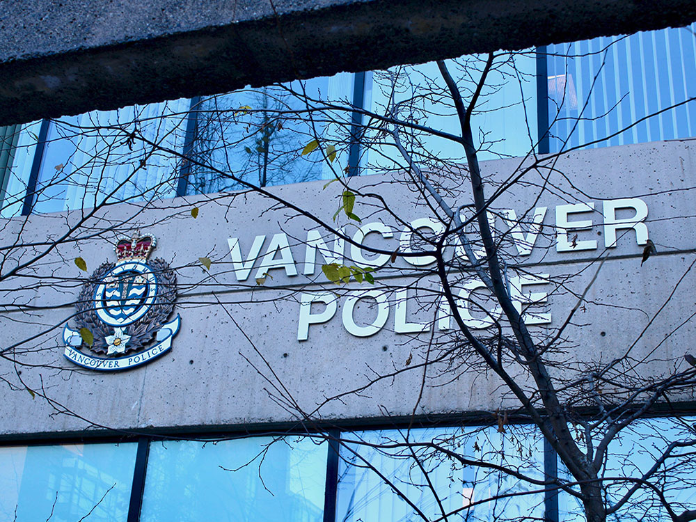 The large ‘VANCOUVER POLICE’ logo is shown on the outside of its building. Leafless trees are in the foreground.