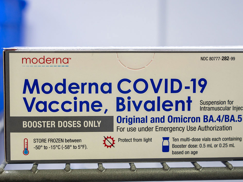 A box of the Moderna bivalent vaccine sits on a metal shelf.