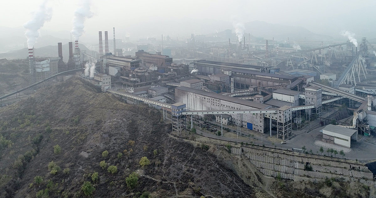 An aerial black-and-white photo shows a sprawling power plant with smoke coming from a number of chimneys.