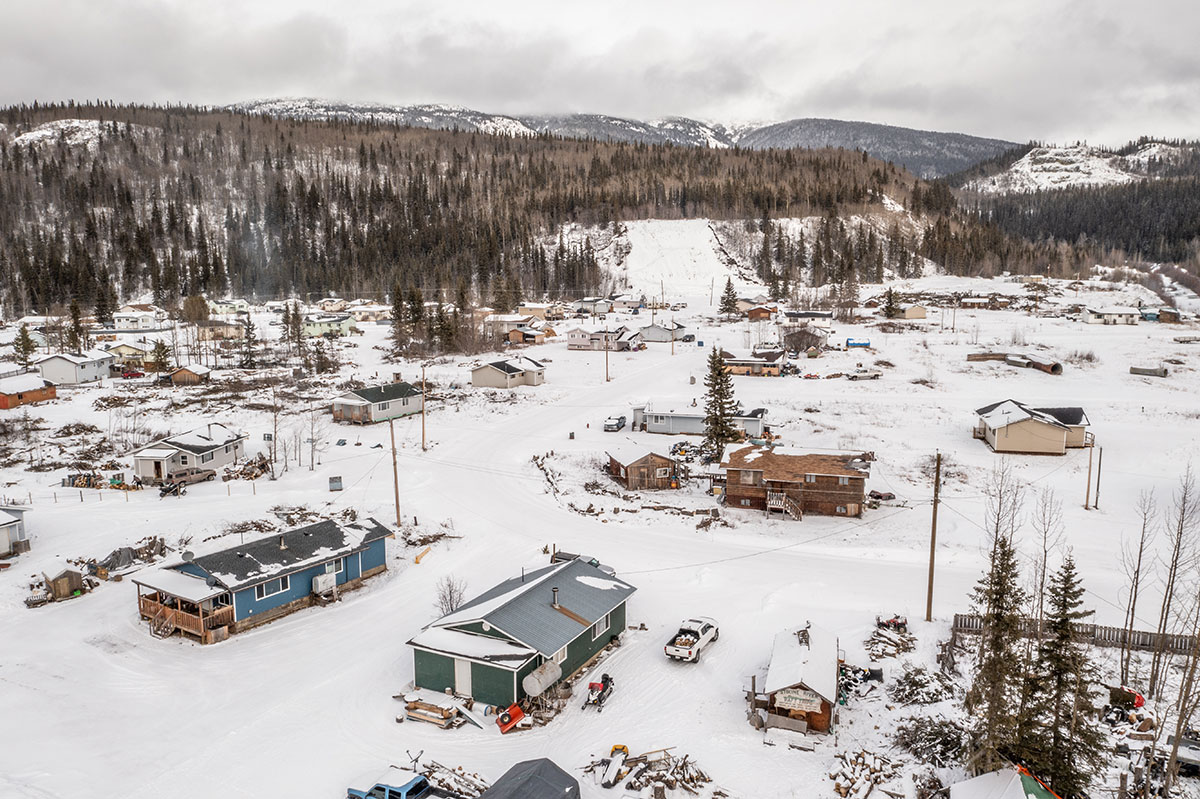 An overhead photo shows a small community of houses. It’s snowy, and there are mountains dotted with evergreens in the background.