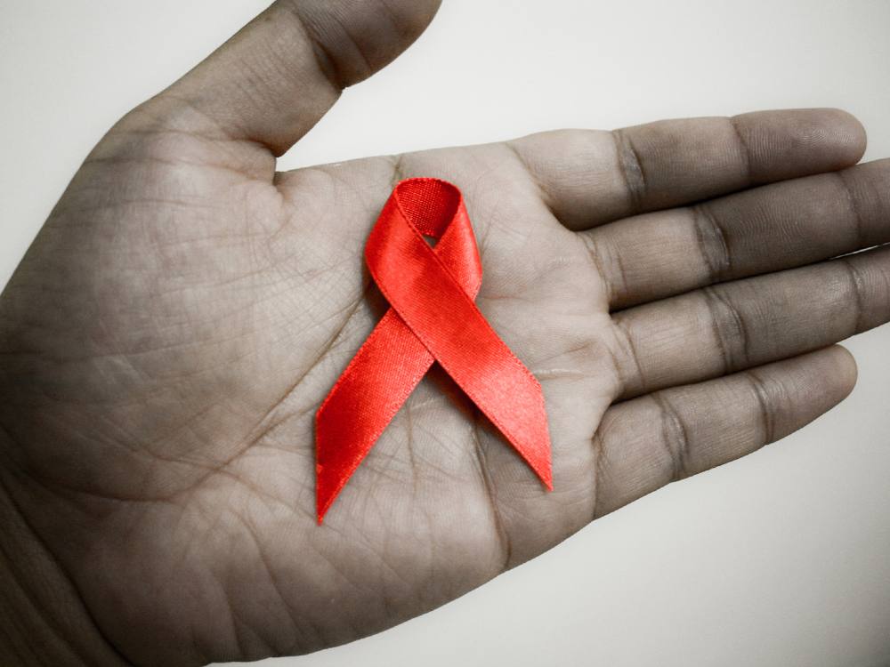 A black and white hand with an HIV-AIDS symbol superimposed on it. 