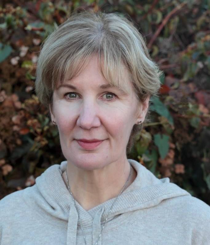 A head and shoulders portrait of a white, middle aged woman with gray hair. 