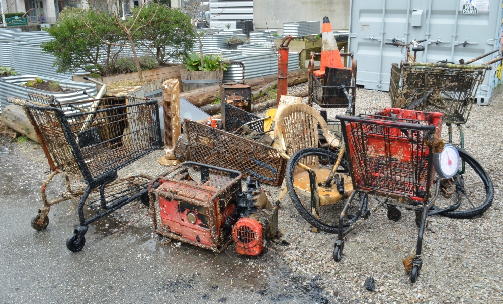 Several shopping carts and a bunch of other trash and detritus, including a lawn chair, that have been pulled out of False Creek.