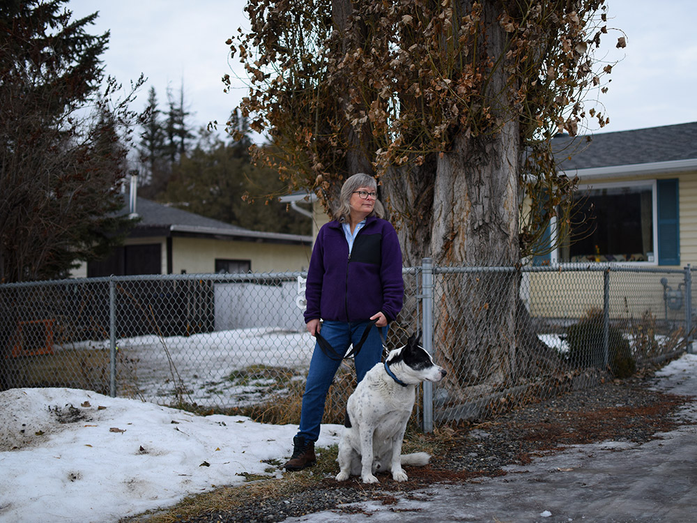 A woman standing with her dog in front of a house