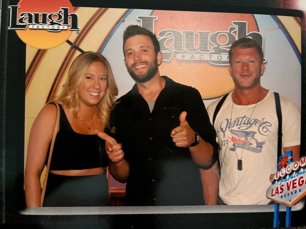 Three people smile and pose for the camera in a digital “Laugh Factory Las Vegas” frame. 