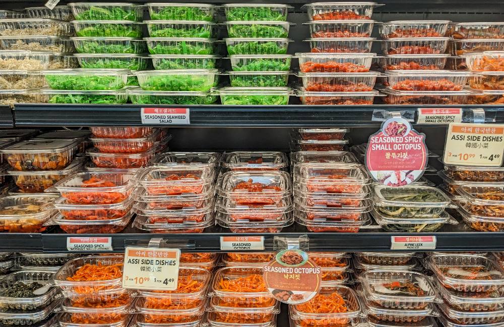 Shelves of plastic clam-shell containers of bright dishes, from seaweed salad to stir-fried squid.