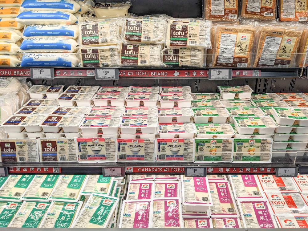 Shelves of packages of different kinds of tofu, from silken to firm to smoked.  
