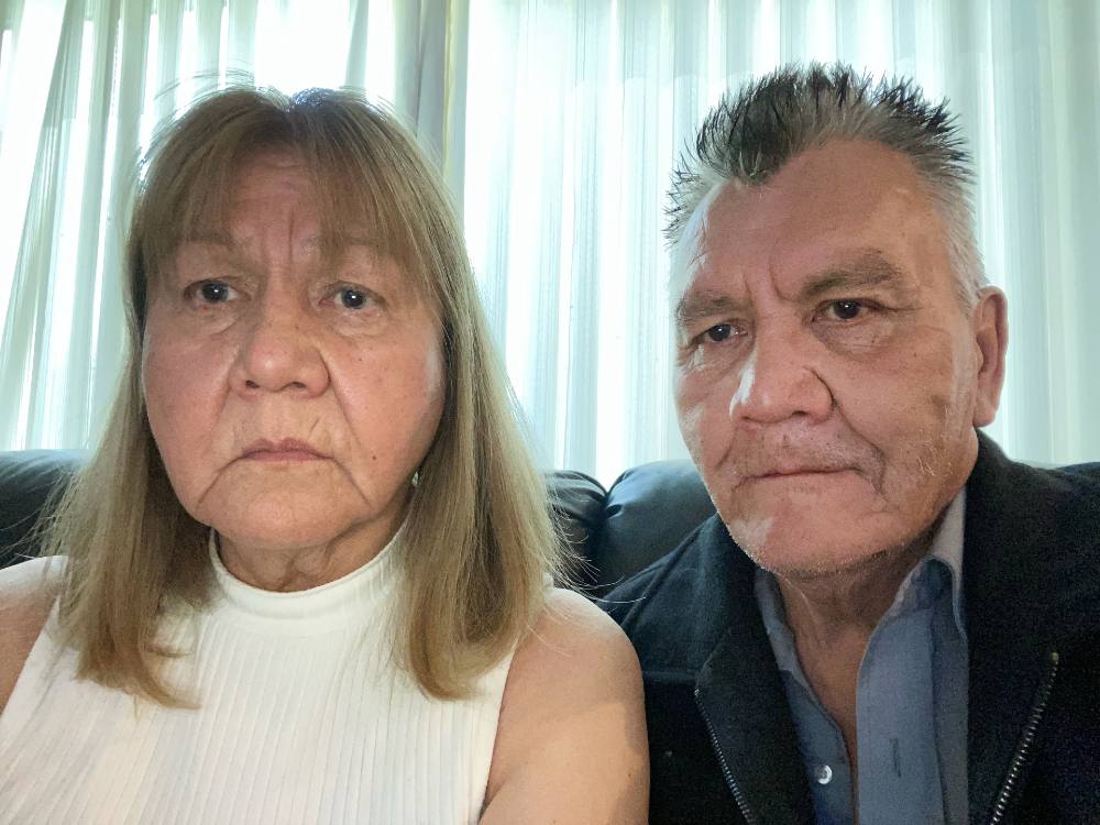 A woman and a man, both appearing to be in their 50s, look into the camera with relatively solemn expressions. 