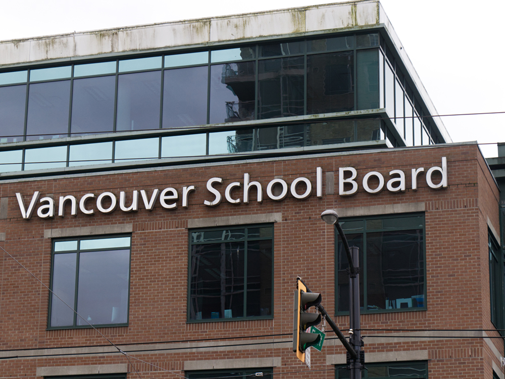 ‘Vancouver School Board’ appears in lettering on the side of a red brick building.