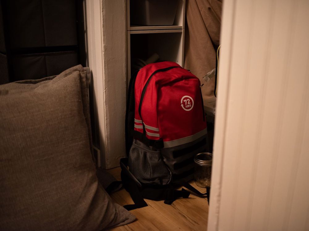 A red 72-hour disaster prep bag sits in a closet. The walls are white. The bag is red. 